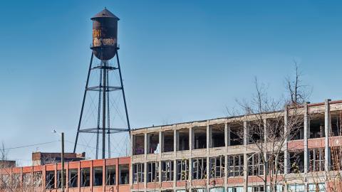 A water tower over a large abandoned industrial building