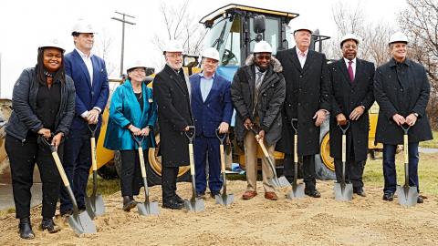 A group of people with hard hats and shovels at a ceremonial groundbreaking