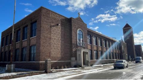 An old brick two-story Catholic school with a blue sky in the background