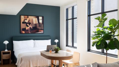 A bedroom with large windows and a dark green wall