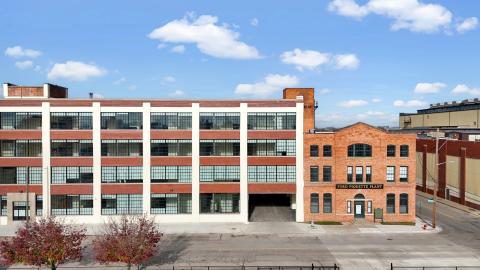 A historic four-story auto plant next to a smaller three-story brick building