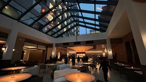 A bar with tables and a glass roof with a taller building next to it